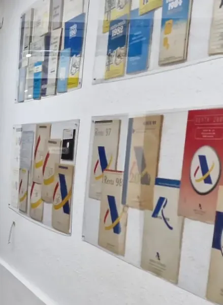 Cuadernillos antiguos de la declaración de la renta enmarcados en la pared